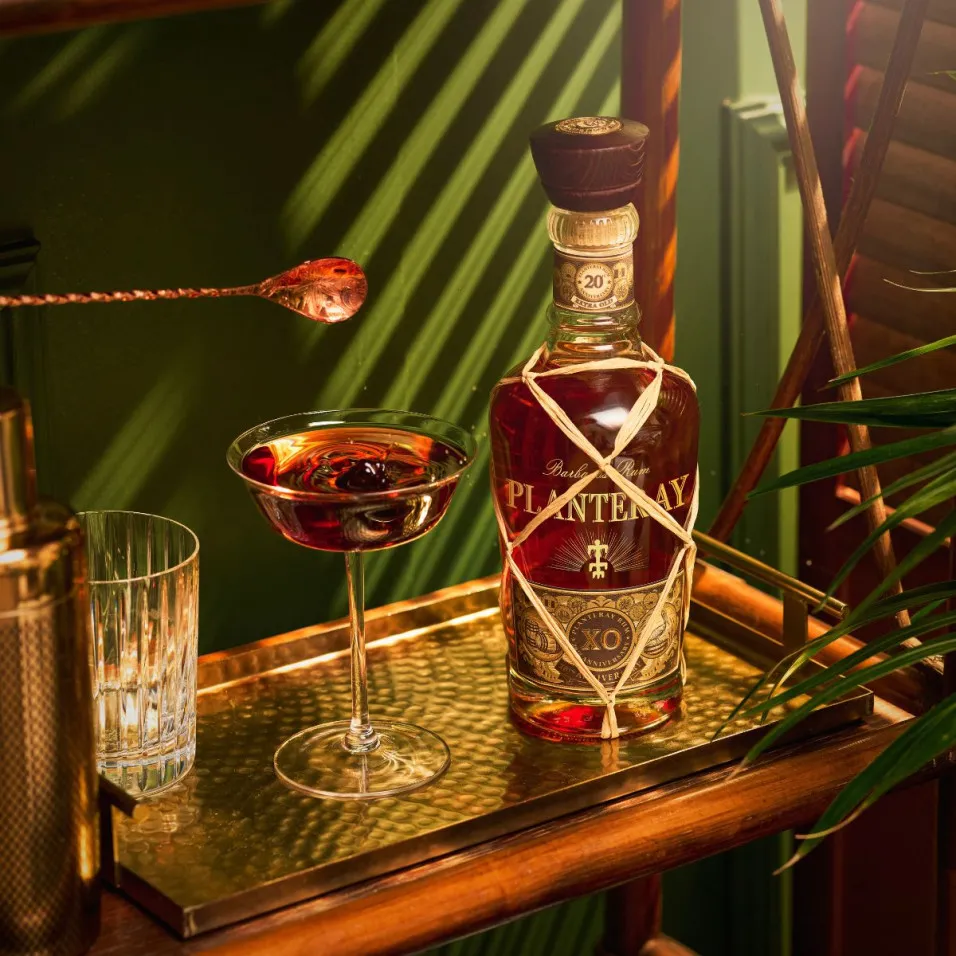 Bouteille Planteray XO 20ème anniversaire et verre de rhum sur plateau doré ambiance rétro